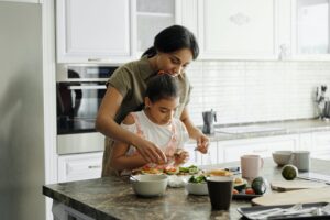 A woman showing her child how to prepare a meal