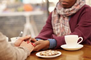 Close up of a woman holding the hands of her friend across the table